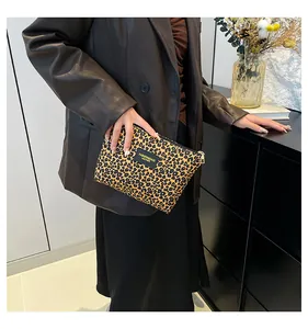 Detail of leopard print makeup bag with black leather label and top zipper closure