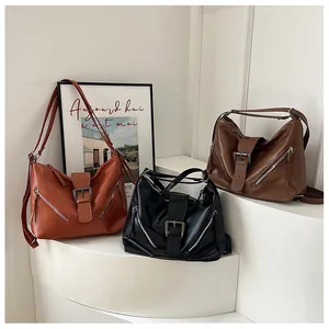 Three leather tote bags in orange-brown, black and dark brown with metal buckles