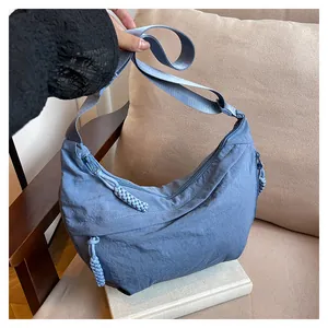 Détail du sac croissant en nylon bleu avec une texture plissée et tirette de zip tressée