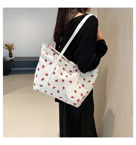 Detailed texture of white corduroy tote bag with red strawberry pattern and mini coin purse