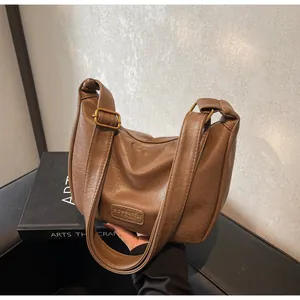 Détail d'un sac Hobo en cuir marron foncé avec boucle dorée vintage et étiquette de marque