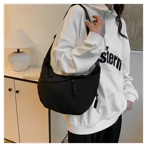 Détail d'un sac demi-lune en nylon noir avec tirette de fermeture tressée et sangle
