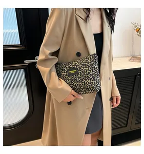 Leopard print makeup bag held by model featuring a leather fashion logo patch