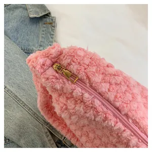 Detail of pink faux shearling texture and golden zipper on a soft dumpling bag