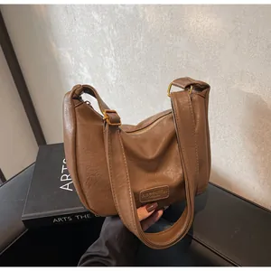 Détail du sac en cuir marron avec boucle dorée et écusson de marque en gros plan