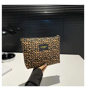 Detailed close-up of leopard print makeup bag featuring a black leather logo patch