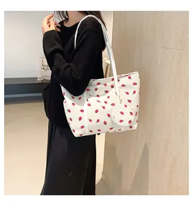 Detail of white tote bag with red strawberry pattern and detachable small charm pouch