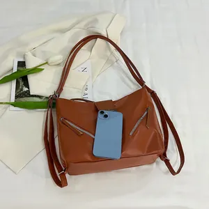 Caramel leather tote bag with zip pockets shown beside phone for size reference