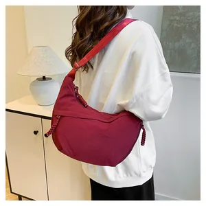 Détail du sac demi-lune en nylon bordeaux avec tirettes tissées et large bandoulière