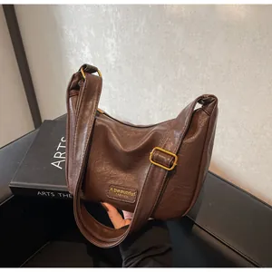 Détail de sac en similicuir marron foncé avec boucle dorée vintage et écusson logo