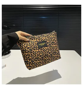 Detail of leopard print toiletry bag with black leather fashion label and zip closure