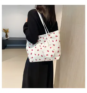 Detail of white corduroy tote bag with strawberry print and matching coin purse on model