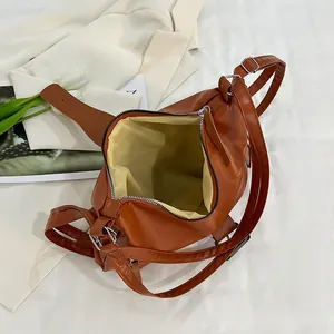 Brown vintage leather tote bag with silver zipper on a beige blazer background