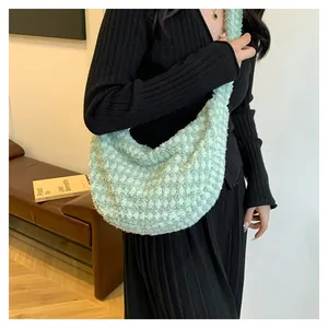 Close-up of the soft green plush texture and pleated design on a puff crossbody bag
