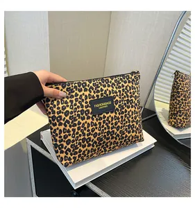 Detail of leopard print cosmetic bag with black zipper and fashion brand label