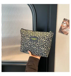 Detail of leopard print cosmetic bag with black leather label and golden zipper puller