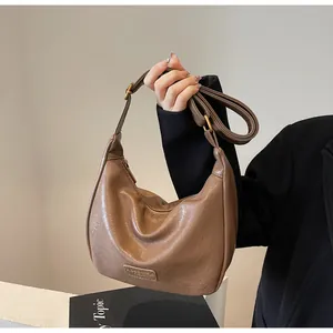 Détail du sac dumpling en similicuir marron avec plaque métallique mode élégante