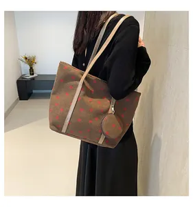 Brown corduroy tote bag with strawberry print and round coin purse shown on shoulder