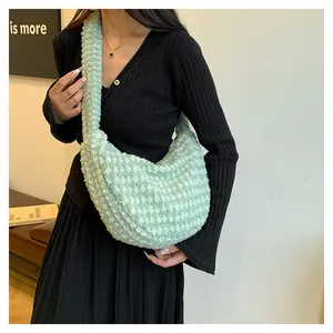 Close-up of soft light green plush crossbody bag with textured fabric on a model