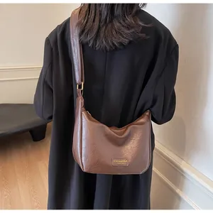 Détail du sac hobo en cuir café foncé avec bandoulière large et étiquette de marque