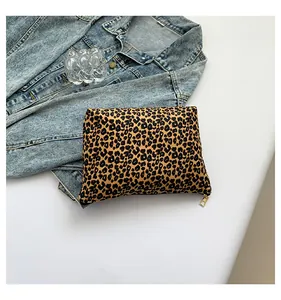 Flat lay of leopard print makeup bag with gold zipper next to denim jacket