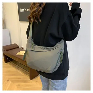 Vue détaillée du dos du grand sac bandoulière en nylon vert foncé avec tirettes de zip tissées