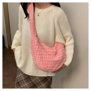 Close-up of pink plush pleated crossbody bag with honeycomb texture on a model