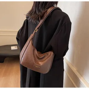 Sac à bandoulière marron en cuir PU avec texture litchi rétro porté sous le bras en ville