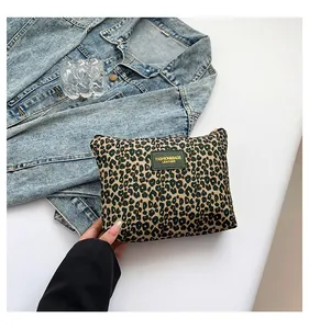 Detail of leopard print cosmetic bag with fashion leather tag on denim background