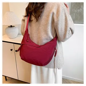 Mannequin portant un sac demi-lune en nylon bordeaux montrant sa grande capacité et son style