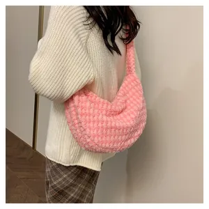 Pink plush shoulder bag with textured surface shown worn over a white knit sweater