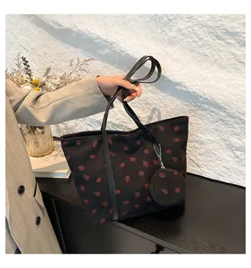 Detailed texture of black corduroy tote bag with red strawberry print and mini pouch