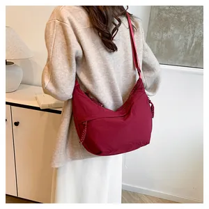 Vue détaillée du sac bandoulière en nylon bordeaux avec sangle réglable et tirettes