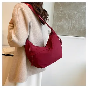 Detalle del bolso de hombro de nailon granate con textura y cordón de cremallera trenzado