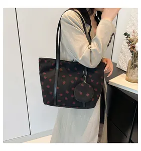 Detail of black corduroy tote bag with red strawberry print and small round coin purse