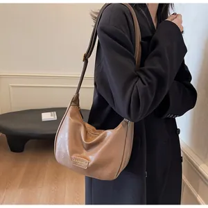 Détail du sac demi-lune caramel en cuir avec logo et finitions dorées élégantes