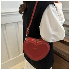 Detailed view of red heart-shaped shoulder bag on model with gold fashion lettering
