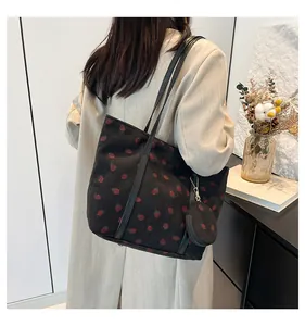 Detail of black corduroy tote bag with strawberry pattern and matching small round purse