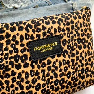 Portable leopard print makeup bag with gold zipper and leather patch on denim base