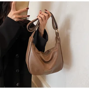 Détail du sac à main marron en cuir plissé avec logo métallique et boucle dorée