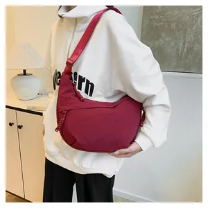 Détail du sac bandoulière demi-lune en nylon rouge avec sangle réglable et tirette tissée