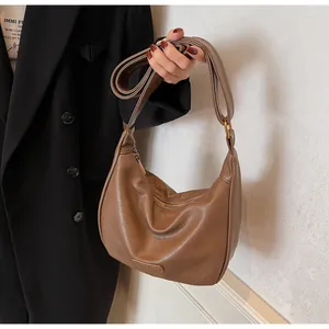 Gros plan du sac hobo marron vintage montrant la texture du cuir et les coutures