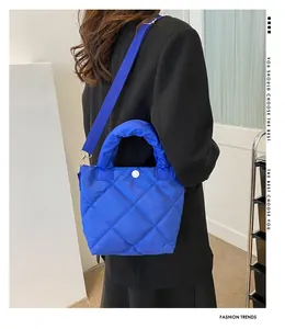 Rückansicht der blauen Stepptasche aus Nylon mit breitem Gurt an schwarzem Anzug