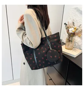 Close-up of black corduroy tote bag featuring red strawberry embroidery and mini pouch