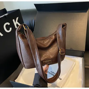 Détail du sac baguette en cuir marron à motif litchi avec ferrures en laiton et bandoulière