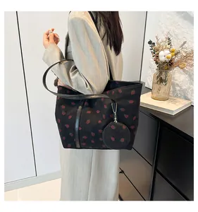 Detail of black corduroy tote bag with strawberry print and hanging coin purse accessory