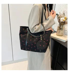 Detail of black corduroy tote bag with red strawberry print and matching coin purse charm