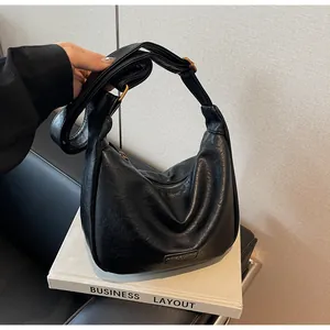 Détail du sac hobo noir avec texture cuir, boucle dorée réglable et plaque de marque