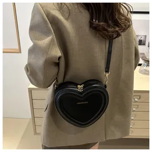 Fashionable black heart-shaped crossbody bag with gold zippers and 3D textured design