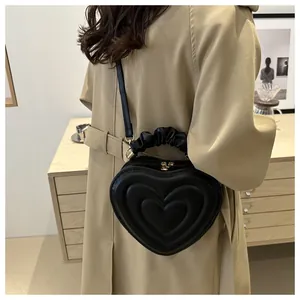 Detail of a black heart-shaped handbag featuring textured layers and a ruched handle
